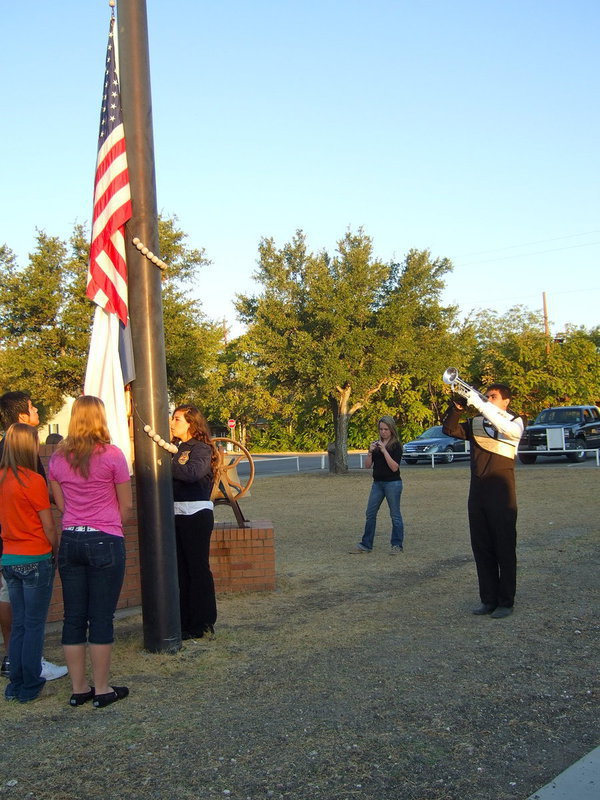 Image: Students continue to raise the American flag as Reid Jacinto continues to play Taps.