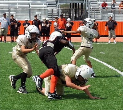 Image: While receiving blocks from teammates Gary Escamilla(40) and Isaac Salcido(80), quarterback Tylan Wallace(2) aims a pass downfield.