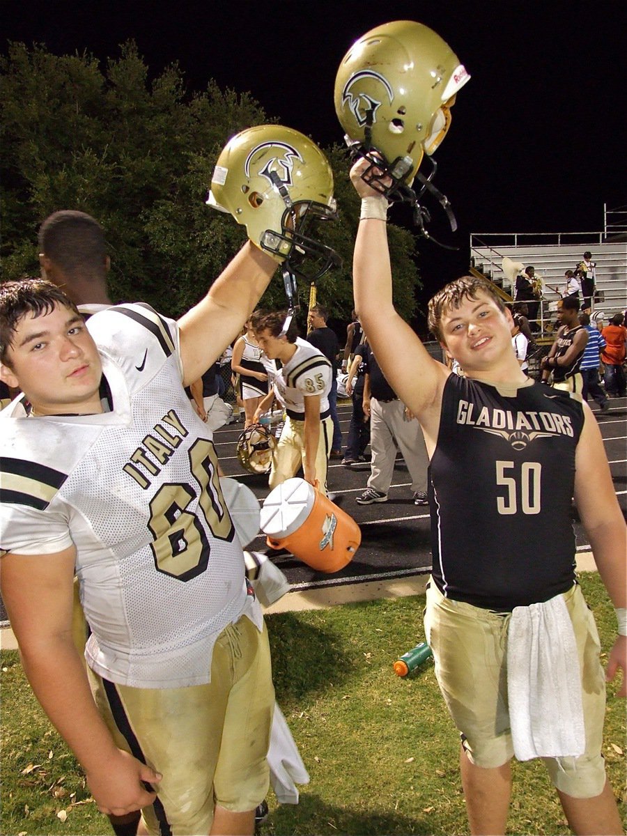 Image: Sophomore linemen Kevin Roldan(60) and Zain Byers(50) raise their Gladiator helmets in triumph.