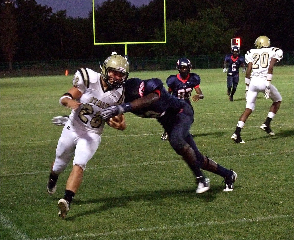 Image: Italy’s Kyle Jackson(28) picks up extra yards around a downfield block by Trevon Robertson(20) before being ridden out-of-bounds by a Mustang tackler.