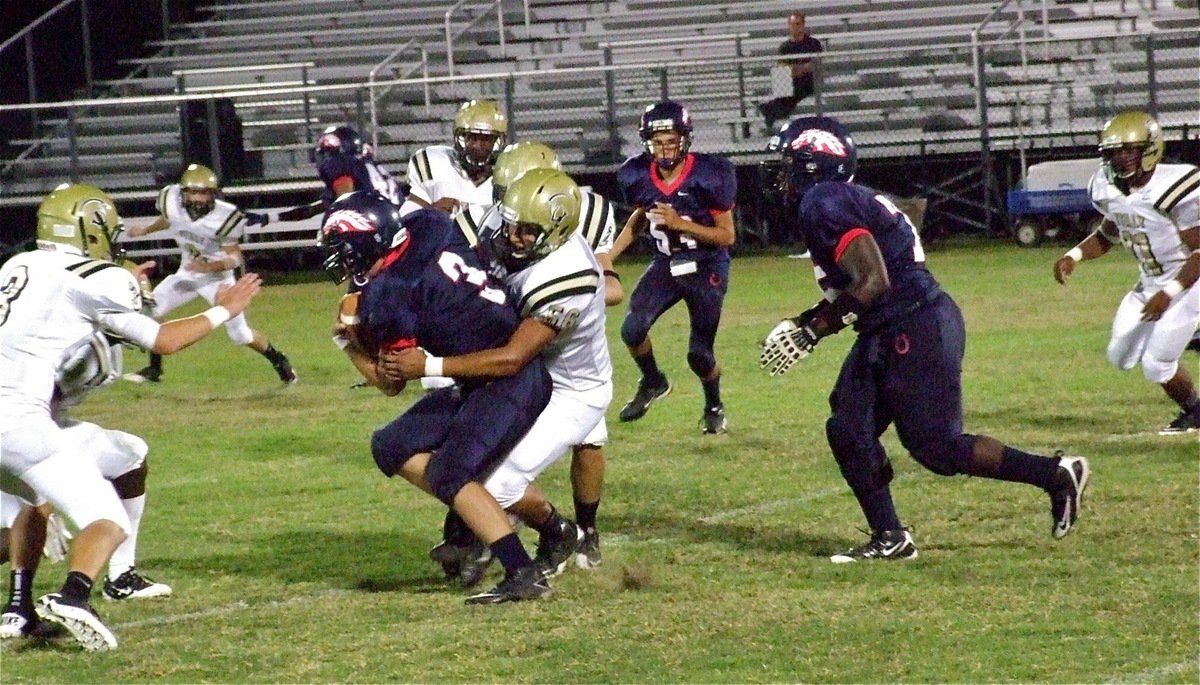 Image: Omar Estrada(56) tackles Mustang quarterback, Cooper Spurgin(3), for a short gain.