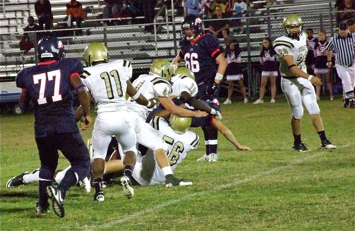 Image: Omar Estrada(56), Ryheem Walker(10) and Ethan Saxon(44) tame a Mustang runner as Jalarnce Lewis(11) and Kyle Jackson(28) keep the play contained.