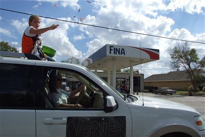Image: Jill Varner tosses candy to the crowd as her mother, Kim Varner, cruises past Varner’s Fina owned and operated by her husband, Stevan Varner.