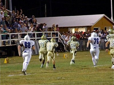 Image: Gladiator defensive tackle Larry Mayberry, Jr.(77) returns an interception past the home stands for a touchdown as teammates Hayden Wood(8) and Eric Carson(24) keep Mayberry protected.