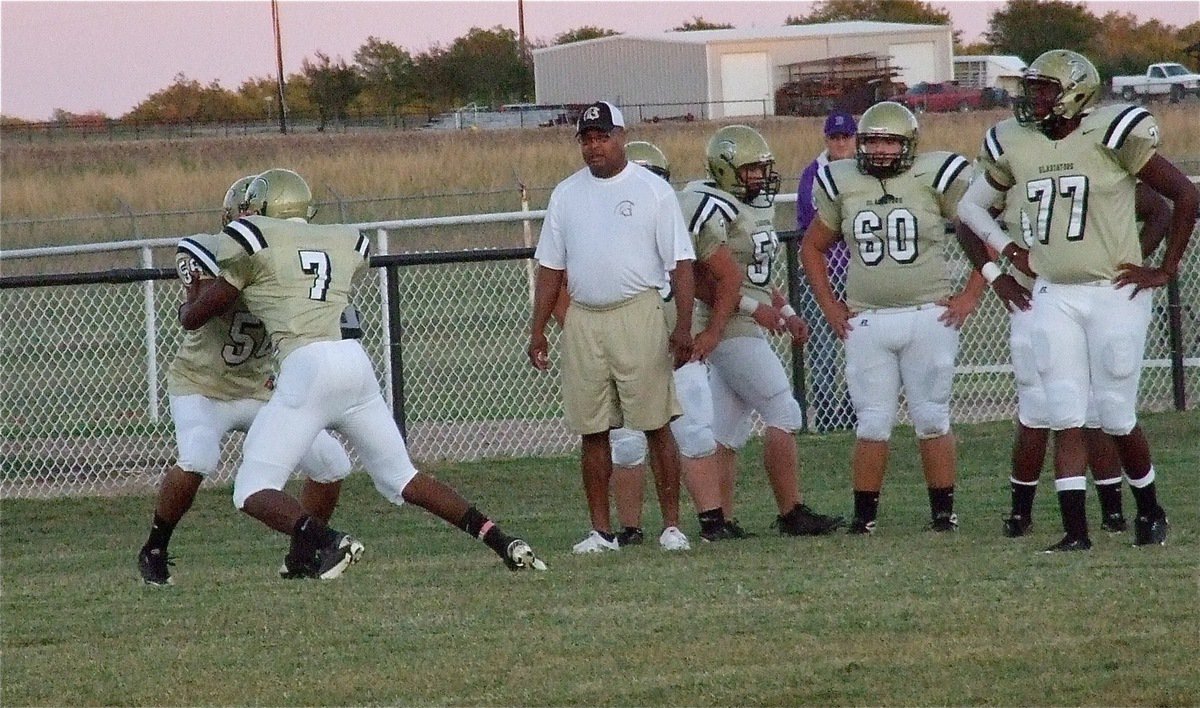 Image: Gladiators Omar Estrada(56) and Paul Harris(7) get rid of the pre-game tension during a blocking drill with instruction from assistant coach Larry Mayberry, Sr. 