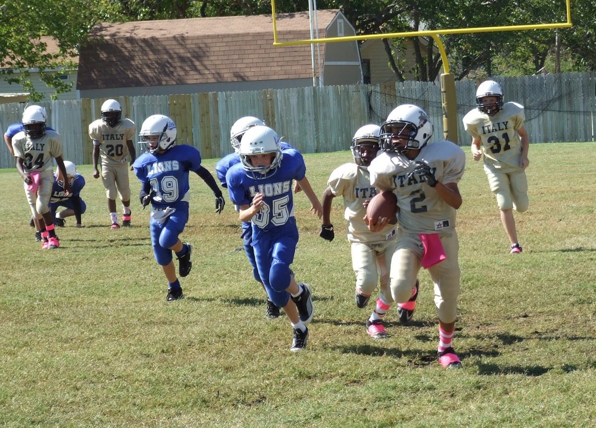 Image: IYAA A-Team quarterback Tylan Wallace(2) breaks away and sprints past the home stands for a big gain into Lion territory.