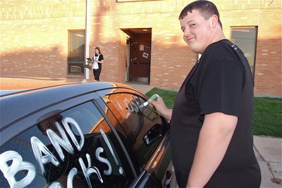 Image: Not thrilled about having his vandalism caught on film but determined to finish, Zac Mercer, decorates assistant band director, Erica Scott’s, car.