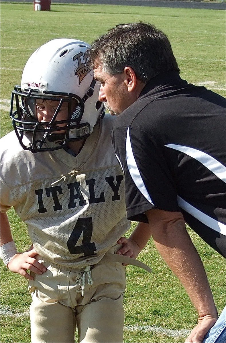 Image: IYAA B-Team head coach Gary Wood tells the play call to Bryce DeBorde(4) during the B-Team action.