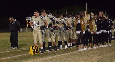 Image: Gladiator head coach, Craig Bales, stands with the team and their cheerleaders during the pre-game prayer.