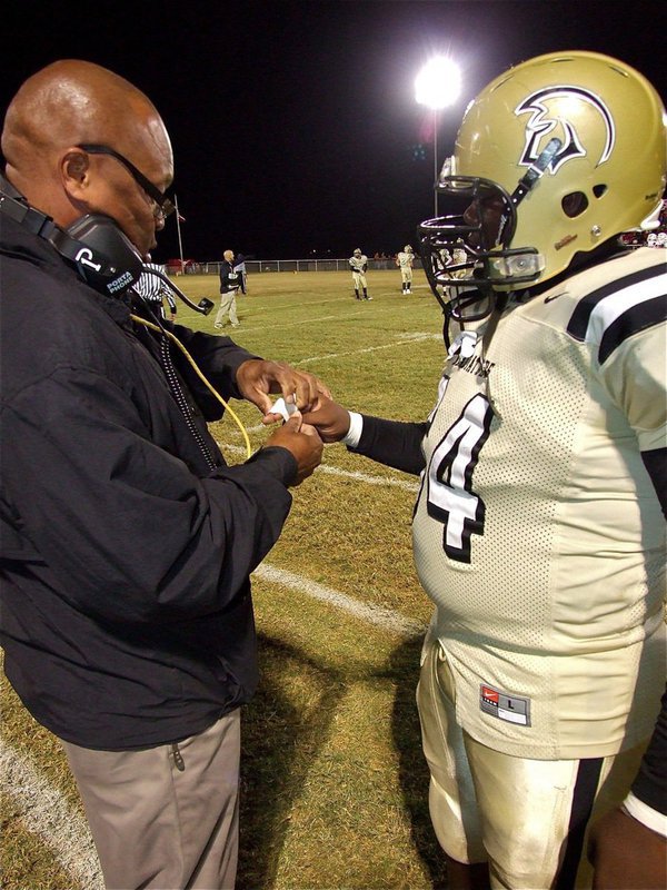 Image: Gladiator assistant coach, Larry Mayberry, Sr., tends to a jammed finger on junior lineman Adrian Reed(64).