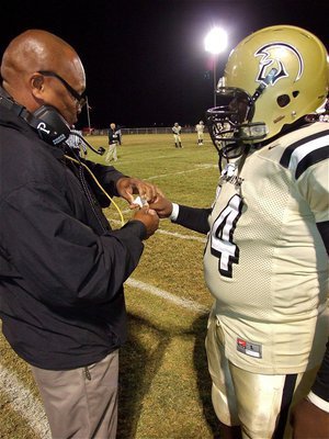 Image: Gladiator assistant coach, Larry Mayberry, Sr., tends to a jammed finger on junior lineman Adrian Reed(64).