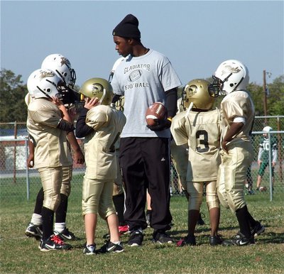 Image: IYAA B-Team assistant coach, Jasenio Anderson, helps his understudies get ready for the kickoff.