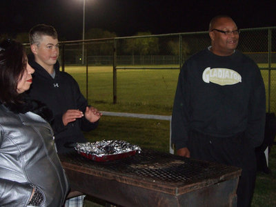 Image: Coach Mayberry grilled the hot dogs for the senior class allowing Sophomore Gladiator Zain Byers to enjoy the heat on a brisk night.