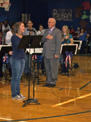 Image: Brittany Goss inviting everyone to stand up and recite The Pledge of Allegiance.
