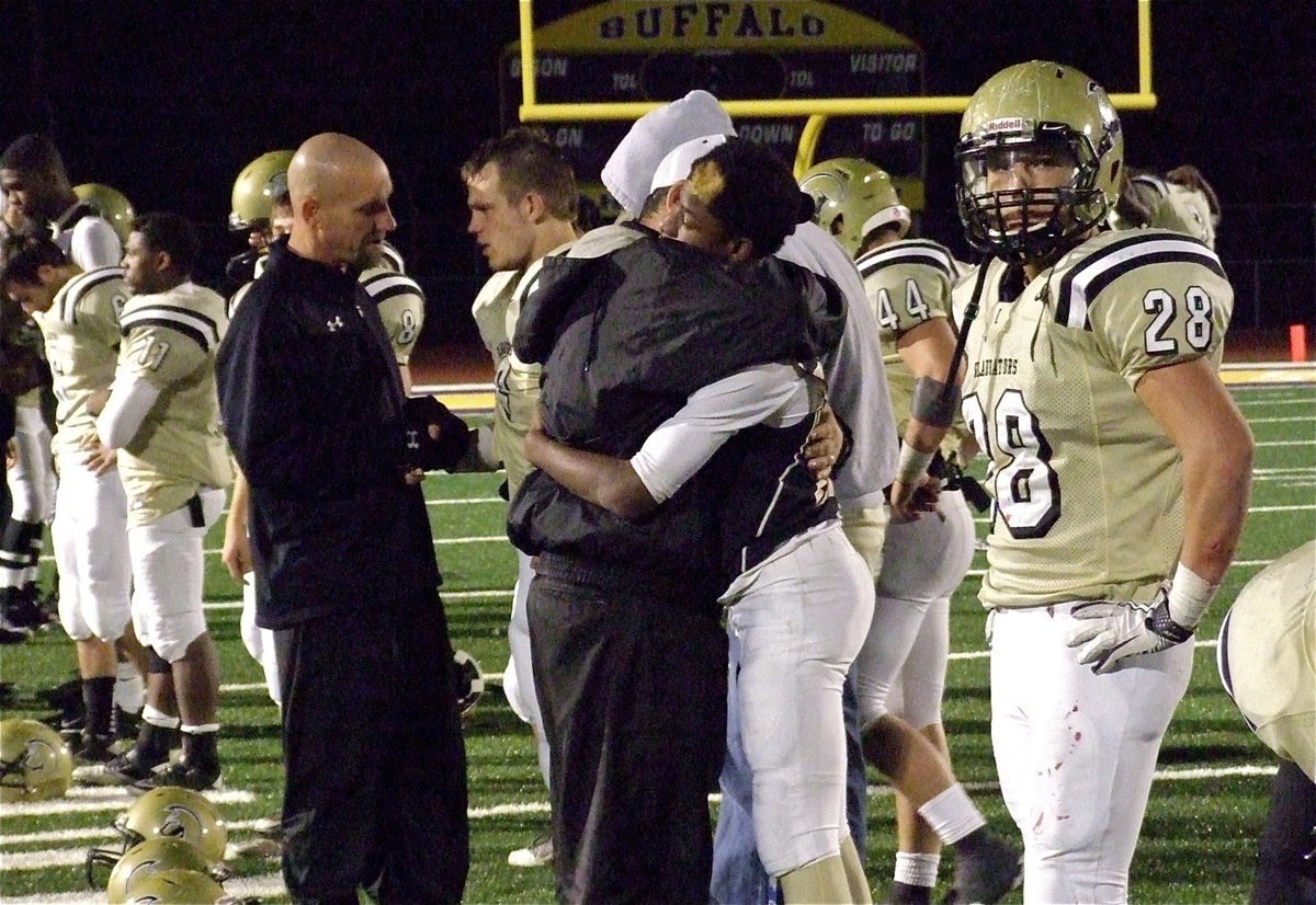 Image: The players lineup after the game and receive congratulatory embraces from the Gladiator coaching staff. Jeff Richters talks with Chase Hamilton(2) while Coach Bales consoles Eric Carson(24).