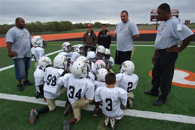 Image: IYAA C-Team assistant coaches Shedric Walker and Michael Davis, along with waterboys Gary Escamilla and Tylan Wallace, look on as head coach Aaron Itson talks with his k-2nd grade players before their Superbowl game against Ferris.