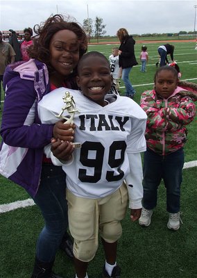 Image: IYAA C-Team Gladiator Byron Davis(99) poses with his mother, Myesha Stanford, as the two display Byron’s Superbowl Runner-up trophy. Byron didn’t allow his little sister, Mariah, to be in this picture.