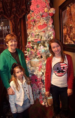Image: Linda Goodman and he two granddaughters, Chloe and Rachel Huskins, pose next to a christmas tree decorated by Mary Teat. Just one of many such trees to welcome guests donating toys for the Italy Christmas Festival.