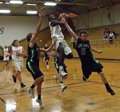 Image: JV Gladiator Marvin Cox(1) finishes the fast break over a pair of Eagles.