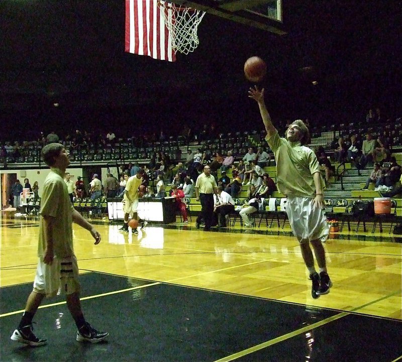 Image: Gladiator senior Brandon Souder is just happy to be back in the game as he puts in a layup during warmups as senior teammate Jase Holden looks on.