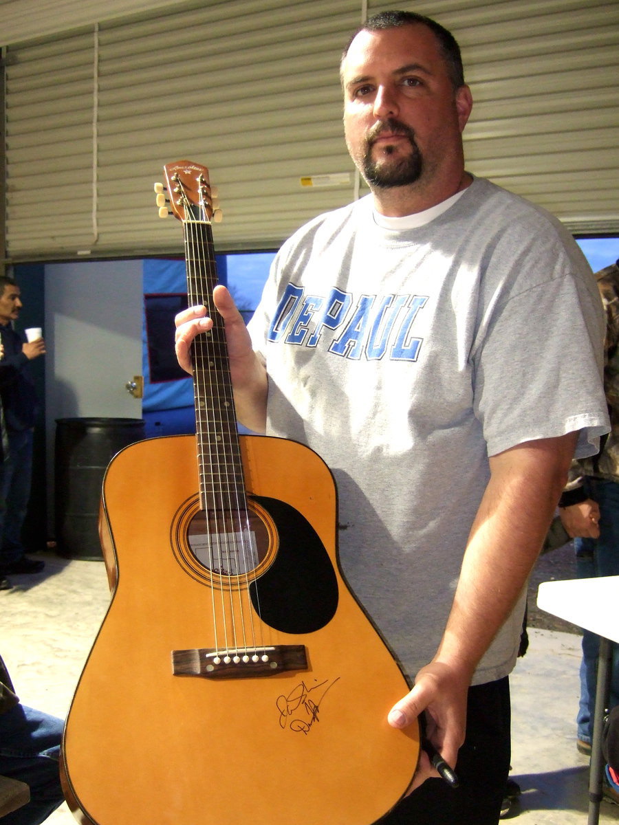 Image: Aaron Itson holding the guitar to be autographed by the bands and then auctioned off.