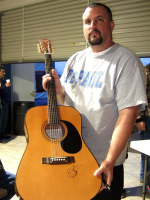 Image: Aaron Itson holding the guitar to be autographed by the bands and then auctioned off.