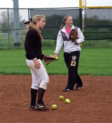 Image: Madison Washington and Jaclynn Lewis take time to gather softballs between hitters.