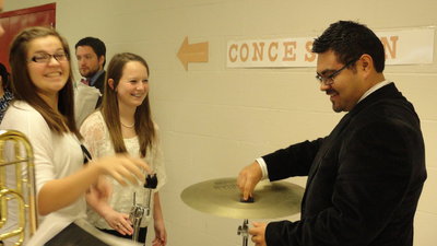 Image: Mr. Perez explains how to tout the cymbal together to Regan Adams and Maddie Pittman.