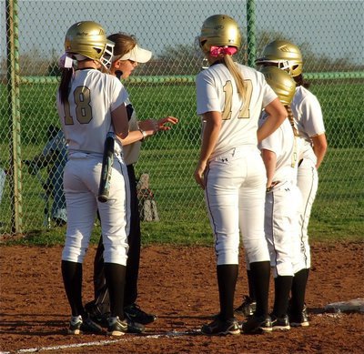 Image: Head coach Jennifer Reeves talks with her hitters and base runners near third base during a timeout.