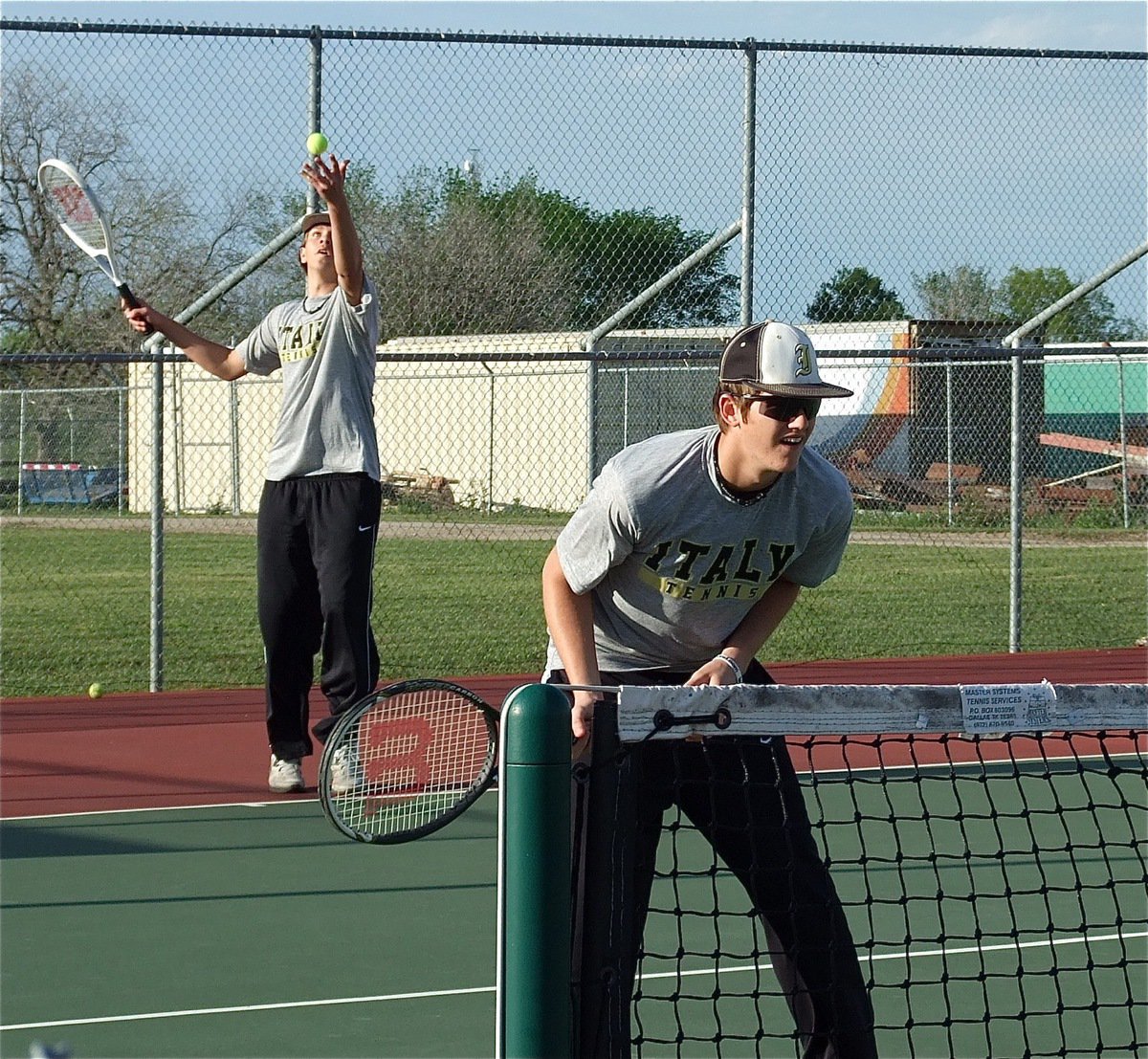 Image: Italy’s Cole Hopkins serves while doubles partner Jase Holden plays at the net.