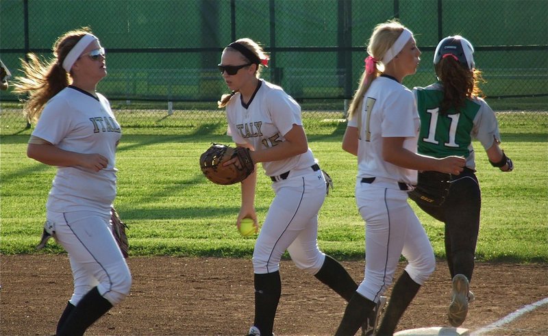 Image: After converging on first base to get the out, Paige Westbrook(10), Jaclynn Lewis(15) and Megan Richards(17) head for their dugout.