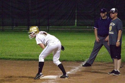 Image: Bailey Bumpus(18) is eager to end the game after reaching first base as Lady Gladiator assistant coach, Michael Chambers, looks on.
