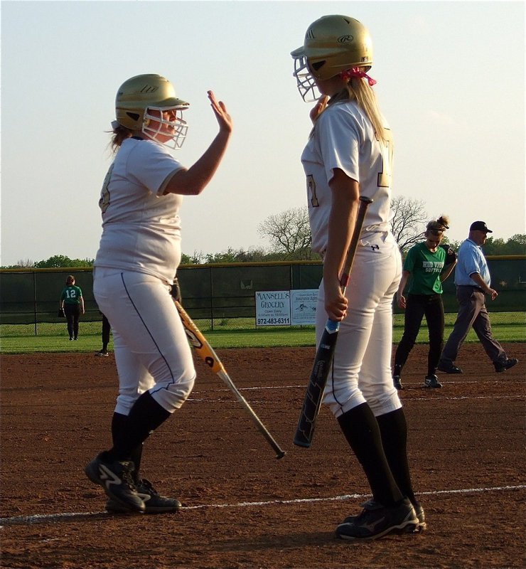 Image: Katie Byers(13) and teammate Megan Richards(17) high-five after Byers crossed home plate.