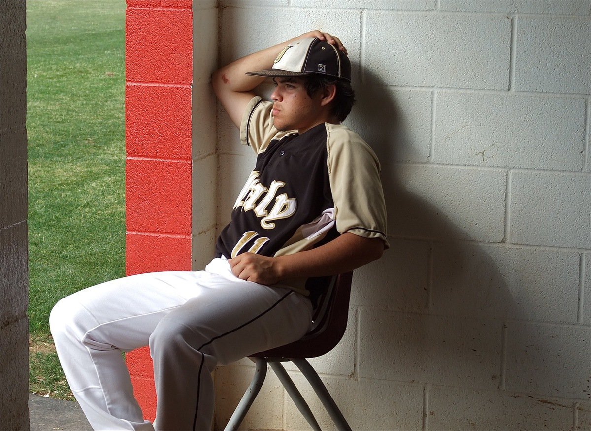 Image: Tyler Anderson, peers thru the doorway of the dugout to catch the action.