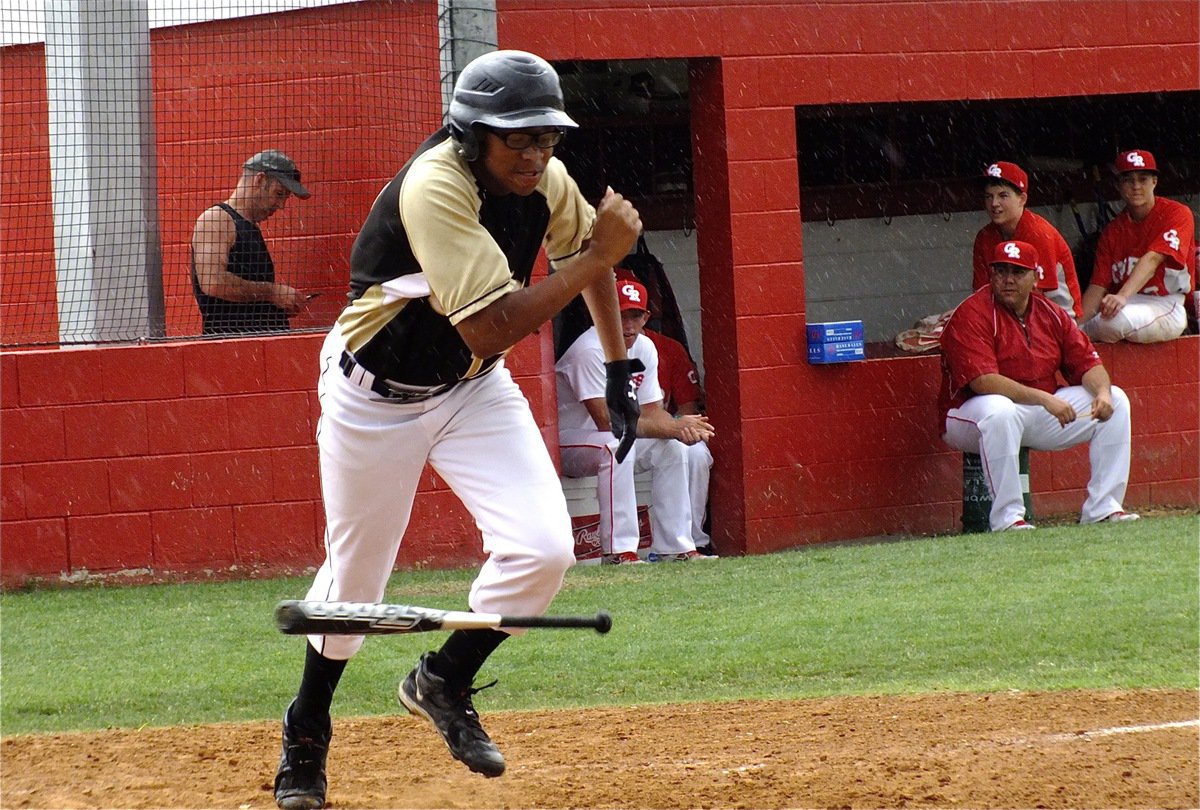 Image: Maximum effort: JV Gladiator, John “Squirt” Hughes, takes off running in the rain after a dropped ball for strike three and reaches first base safely.