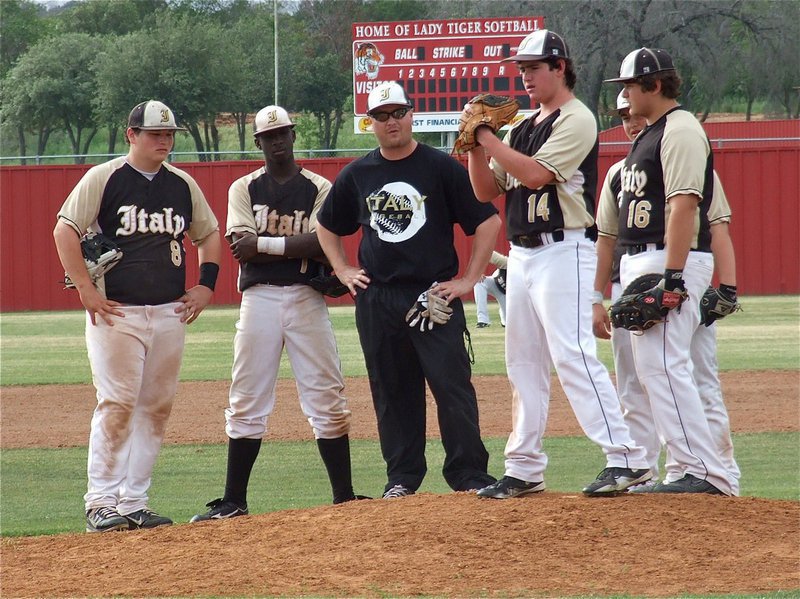 Image: Italy’s infielders, along with Coach Ward, look on as, Kyle Fortenberry(14), takes the mound.