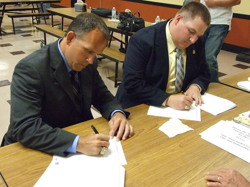 Image: Braswell and Godwin sign their contracts after the meeting.
