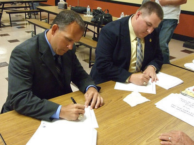 Image: Braswell and Godwin sign their contracts after the meeting.