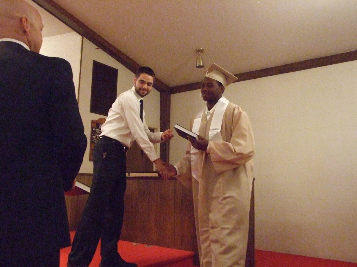 Image: Youth Pastor from Central Baptist Church, Jeremy Beggs, offers a Bible to senior Larry Mayberry.