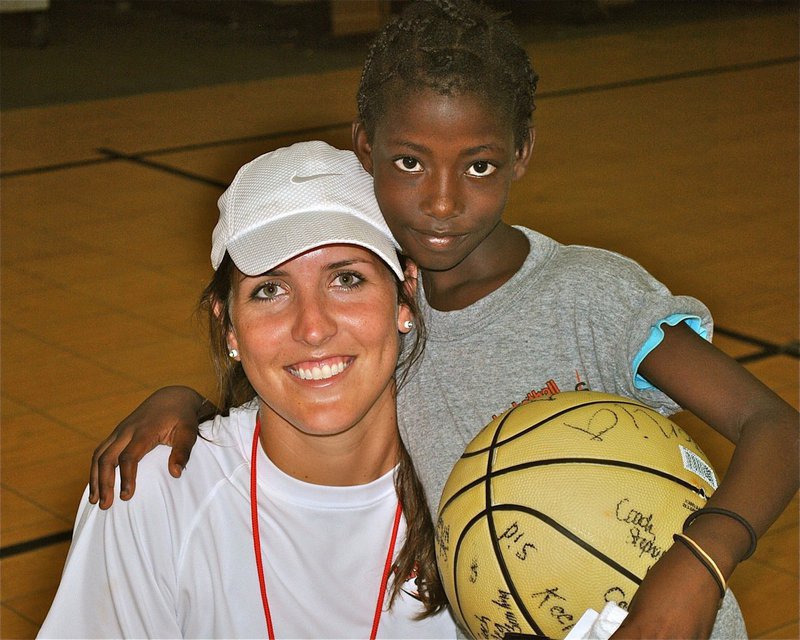 Image: Megann Mae Lewis Harlow, a 2007 graduate of Italy High School, autographs a donated basketball giving to a young camper during the 13th Annual Basketball Smiles Camp held in Nassau, Bahamas for disadvantaged youth.