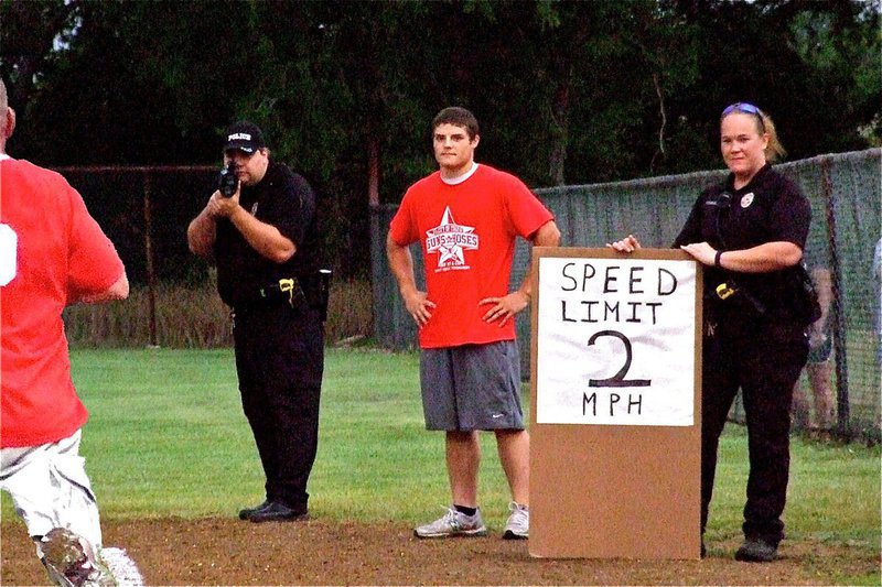 Image: I.F.D.’s Ethan Simon seems concerned with the speed trap put in place along the first base line by I.P.D. officers Eric Tolliver and Jamie Thompson.