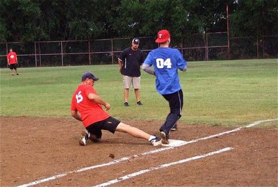 Image: First baseman, Bobby McBride(15), keeps his foot on the bag to get Officer Daniel Pitts out with Umpire Hank Hollywood making the call.
