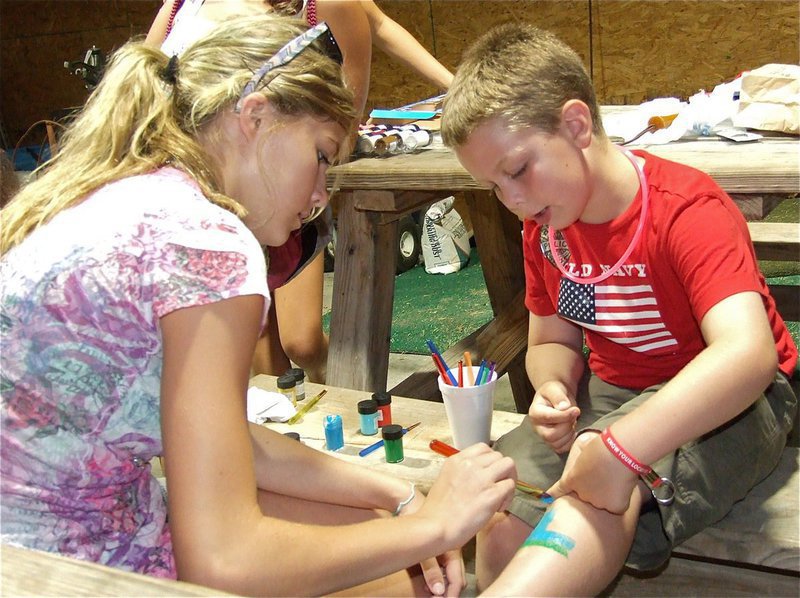 Image: Halee Turner leg paints Brock Hollwywood to help raise money for “Shop with a Cop”