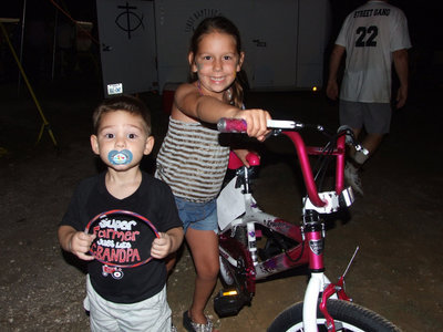 Image: Six year old, Ella Hudson, receives the girl’s bicycle, as cousin, Brady, helps.