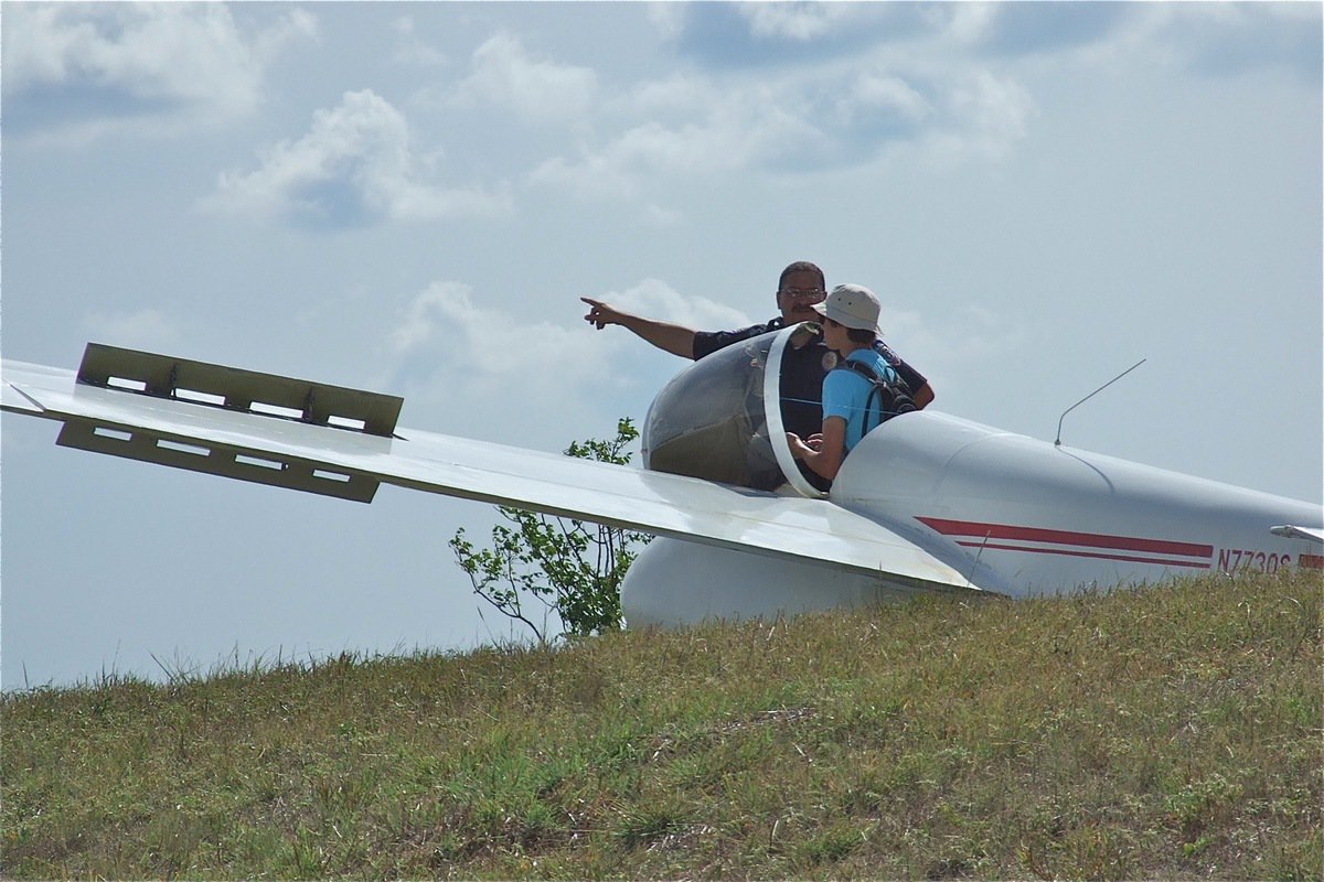 Image: Would like to be a fly on the wing during this line of questioning. The glider is one of twenty planes competing in the 2012 1-26 Championships and touched down after being airborn for 2.5 hours.