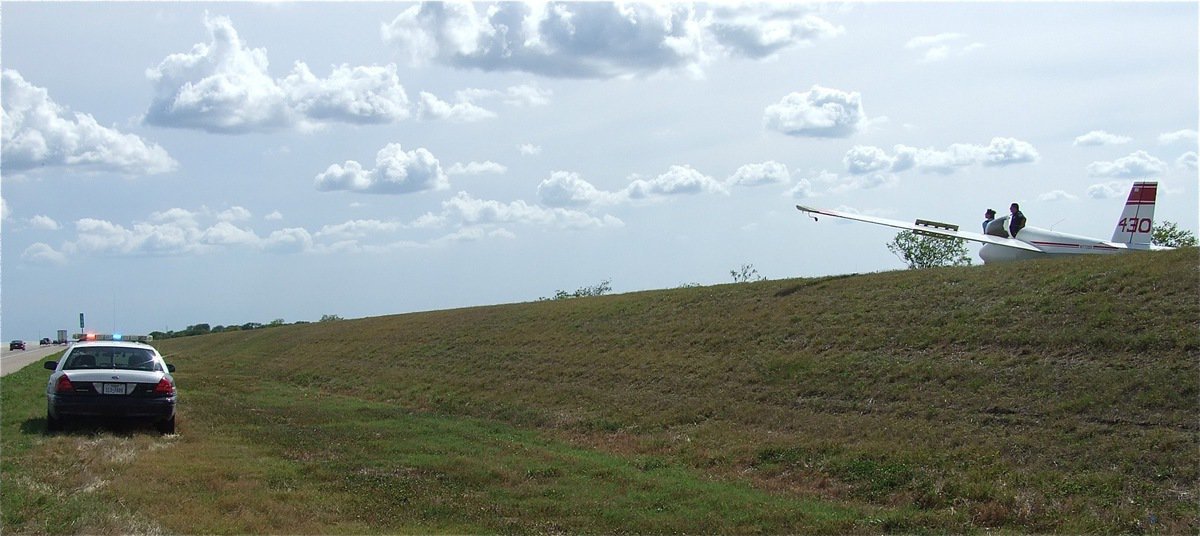 Image: At first glance, Milford’s Police Chief Carlos Phoenix appears to be executing an “air” traffic stop along Highway 35 south of Italy. Actually, Chief Phoenix is investigating the plight of glider 430 as it rests safely away from traffic after loosing air during a race.