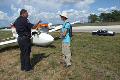 Image: Chief Phoenix questions 17-year old pilot Jacob Fairbairn regarding his unusual situation. To a member of the soaring community, however, unplanned glider landings are fairly common. It’s still up in the air who will win the trophy but young Fairbairn handles the situation like a champ.