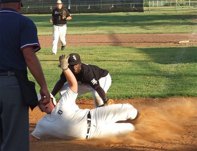 Image: First baseman Kevin Roldan(20) backs up Marvin Cox(1) as the pitcher makes the tag at the plate to keep a Dawson run from counting.