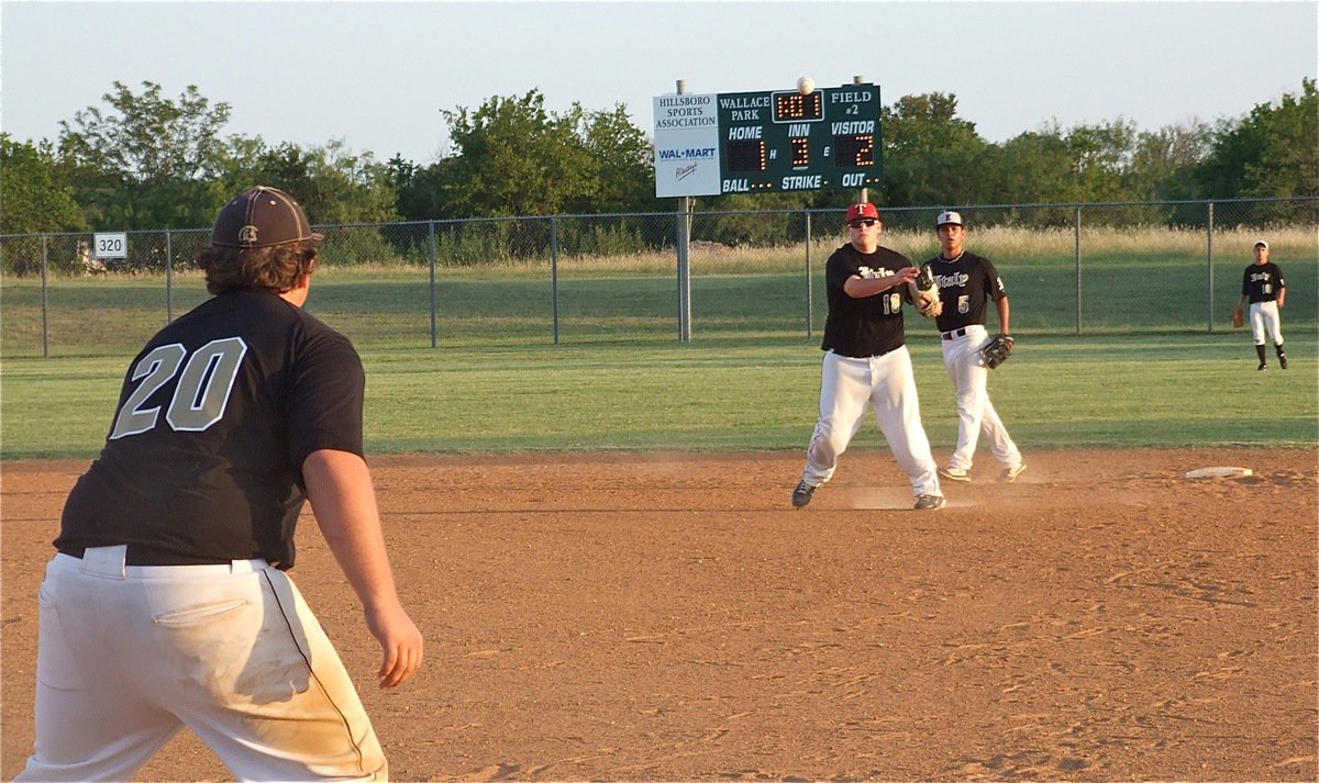 Image: Second baseman John Byers(18) fields a grounder and delivers a throw on the money to Kevin Roldan(20) for the out.