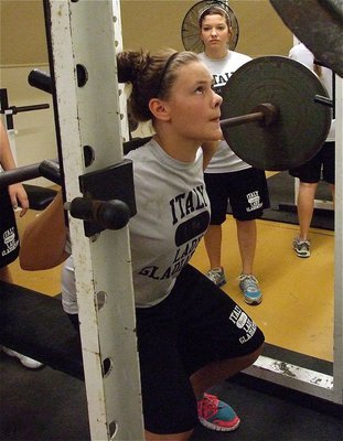 Image: Senior Morgan Cockerham looks on as freshman Lillie Perry completes her lift.